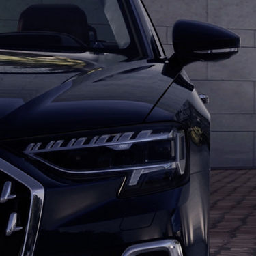 Close-up of a car's front grille and headlight with a sleek design.